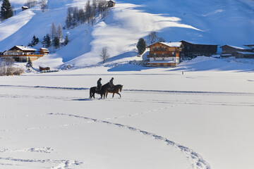 Schönes Winterpanorama mit zwei Reitern bei Bramberg am Wildkogel, im Salzburger Land, Österreich.