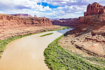 Muddy, winding Colorado River through the arid desert, red sandstone landscape of Canyonlands...