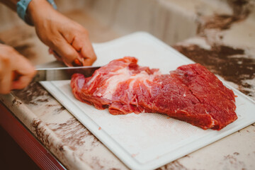 Cook preparing red meat for the barbecue. Barbecue is a delicacy made from fresh or processed meat,...