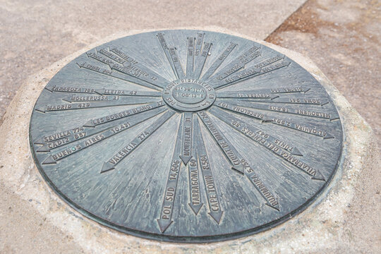 a metallic circle indicating the direction and distance to different locations in the world from the park of Sant Eloi in Tarrega, Province of Lleida, Catalonia, Spain