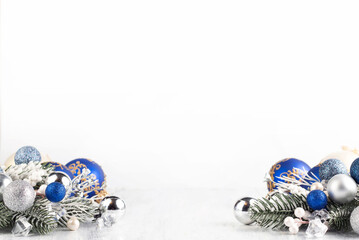 On a light background there is a decor of blue and silver Christmas tree decorations, spruce...