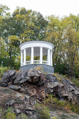 White gazebo on a stone slope in the park.