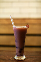 A glass of grape juice with a single grape