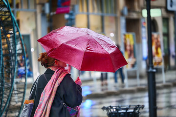 Ludzie pod parasolem w czasie deszczu i wiatru. 