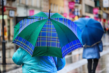 Ludzie pod parasolem w czasie deszczu i wiatru.  - obrazy, fototapety, plakaty