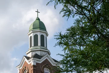 Deurstickers A white colored tall wooden Catholic circular-shaped steeple of a religious building. The exterior decorative clerestory windows have green trim. The peaked wood roof has decorative molding designs.   © Dolores  Harvey