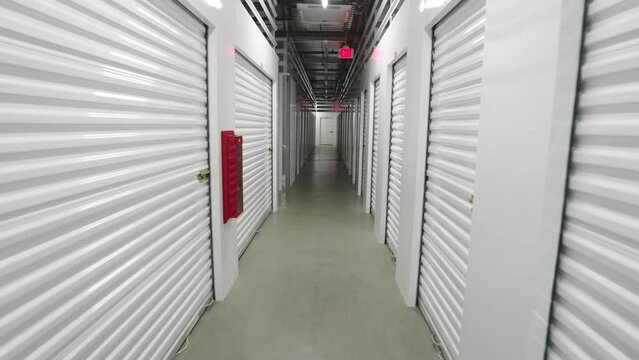 Walking along deserted clean long corridor with a narrow passage, automatic lighting, fire safety, fire extinguisher. Secure and reliable storage solutions. High quality 4k footage
