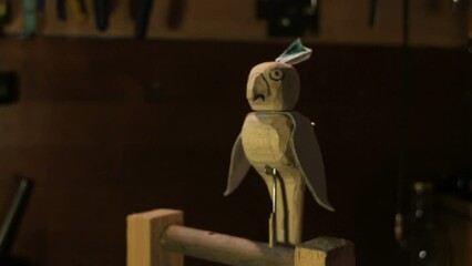 parrot turns its head and flaps its wings, funny wooden toy automaton, workshop interior
