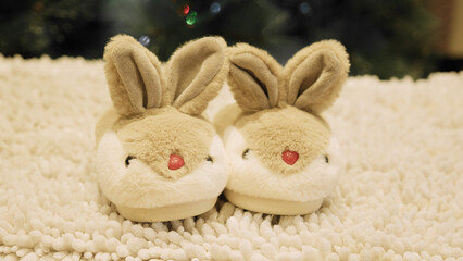 Close up on furry bunny sleepers on white carpet in front of Christmas tree. High quality photo