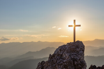 Silhouettes of crucifix symbol on top mountain with bright sunbeam on the sunset background - obrazy, fototapety, plakaty