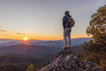 Hiker with backpack standing on top mountain sunset background. Hiker men's hiking living healthy...
