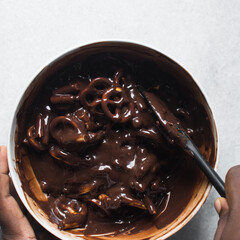 Top view of chocolate pretzel fudge in a white ceramic bowl, process of making chocolate fudge