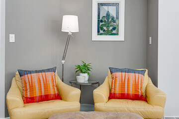 Cozy Living Room Corner with Vibrant Orange and Red Pillows on a Soft Yellow Loveseat, Floor Lamp,...