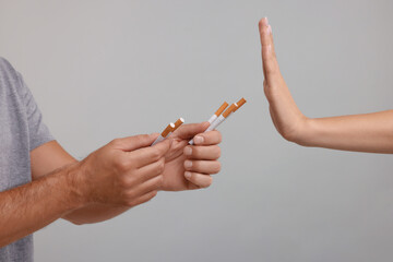 Stop smoking concept. Woman refusing cigarettes on grey background, closeup