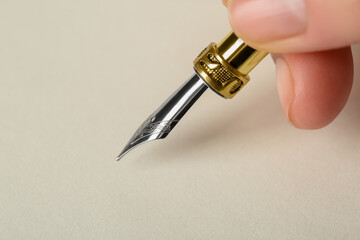 Woman with fountain pen above light paper, closeup. Space for text