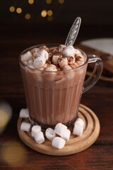 Cup of aromatic hot chocolate with marshmallows and cocoa powder on table, closeup