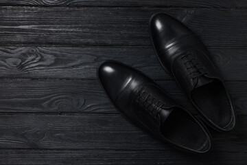 Pair of leather men shoes on black wooden background, top view. Space for text - obrazy, fototapety, plakaty