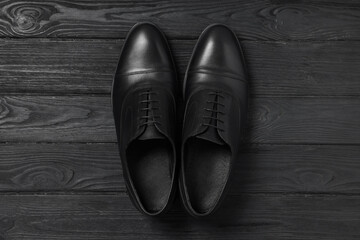 Pair of leather men shoes on black wooden background, top view