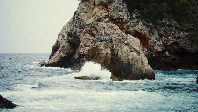 Waves crashing below Fort Bokar and Dubrovnik’s city walls on a cloudly day, Croatia.