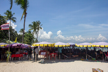 Tourists sat under beach restaurant umbrellas