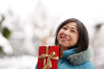 雪の中でプレゼントを持つ中年女性