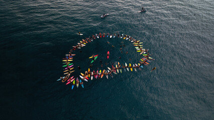 A group of surfers in a circle in the ocean in Hawaii