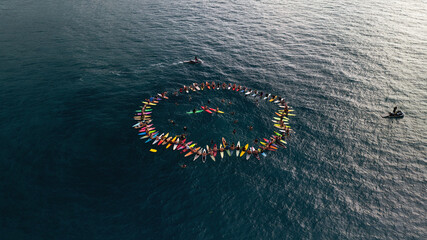 A group of surfers in a circle in the ocean in Hawaii
