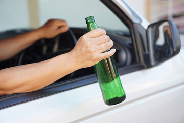 Close up a driver holds bottle of beer in car. Concept , Campaign for don't drive, don't drink alcohol that can cause car accident and illegal. Dangerous driving when drunk.                         