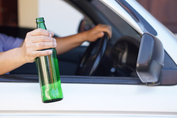 Close up a driver holds bottle of beer in car. Concept , Campaign for don't drive, don't drink alcohol that can cause car accident and illegal. Dangerous driving when drunk.                