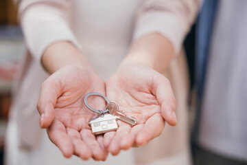 Happy woman a landlord hands keys signifying new home buy. Real estate concept close-up portrays success security and tenant happiness. Landlord's hand gives keys to the camera. Give me the key - obrazy, fototapety, plakaty