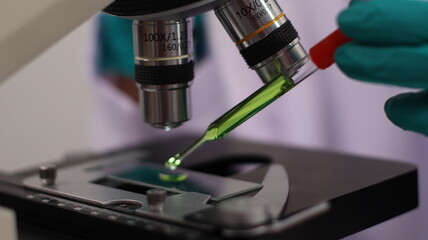 laboratory setting with colorful liquids in test tubes and a person wearing a lab coat and gloves.