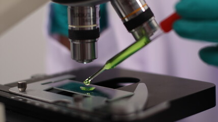 laboratory setting with colorful liquids in test tubes and a person wearing a lab coat and gloves.