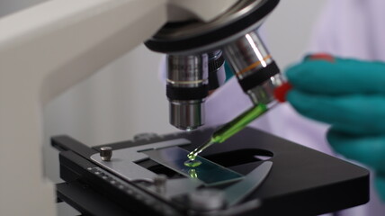 laboratory setting with colorful liquids in test tubes and a person wearing a lab coat and gloves.