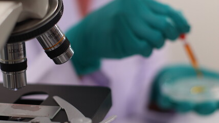 laboratory setting with colorful liquids in test tubes and a person wearing a lab coat and gloves.