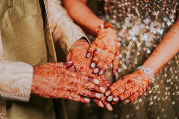 Indian bride and groom hand with henna showing their engagement ring