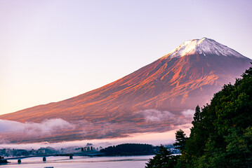 	夜明けに徐々に赤く焼けていく富士山と朝霧で幻想的な裾野の街