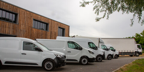 White commercial delivery panel vans in row mockup front Warehouse Building