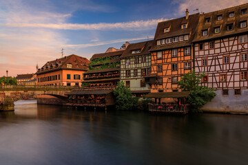 Ornate traditional half timbered houses with blooming flowers along the canals in the Petite France district of Strasbourg, Alsace, France at sunset