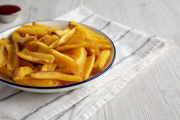Homemade French Fries with Ketchup on a white wooden background, side view. Copy space.