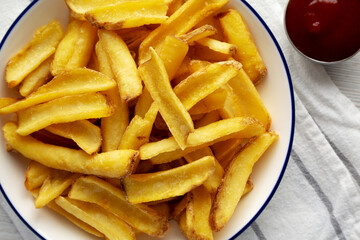 Homemade French Fries on a Plate on a white wooden background, top view. Close-up.