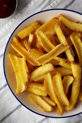 Homemade French Fries on a Plate on a white wooden background, top view. Flat lay, overhead, from above.