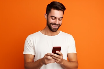 man looking at phone standing isolated on orange background