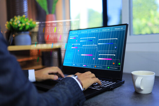Project management concept with businessman working on schedule on laptop screen and marking color note on calendar for meeting appointment in office desktop