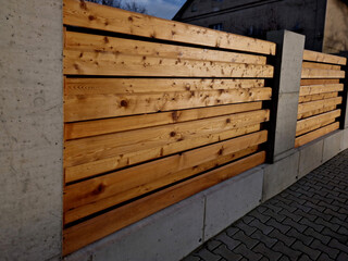 wooden fence made of natural planks. the columns are made of roughly plastered white columns. full fencing made of horizontally placed boards. adjacent to the land is a bed of shrubs - Powered by Adobe