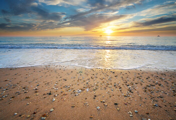 Sand and rocks on seashore at sunset