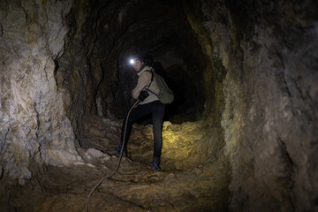 Adult Woman Adventurer Descending Carefully with Help of a Rope an Underground Mountain Cave