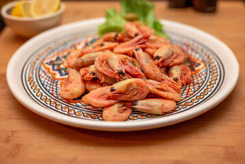 Top view from cooked shrimps on a plate with lemon on the site. 