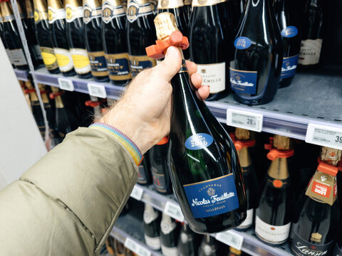 Paris, France - Nov 10, 2023: POV of a male hand choosing a bottle of Nicolas Feuillatte champagne, preparing for Christmas and New Year's Eve celebrations