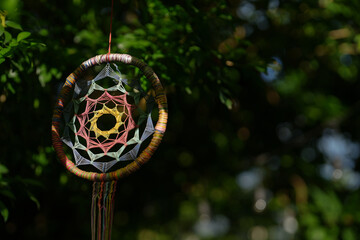 Colorful handcrafted dream catcher with rope hanging under the tree. Dreamcatcher handmade.