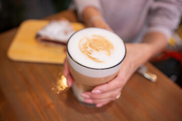 woman hands with latte on a wood table in cafe